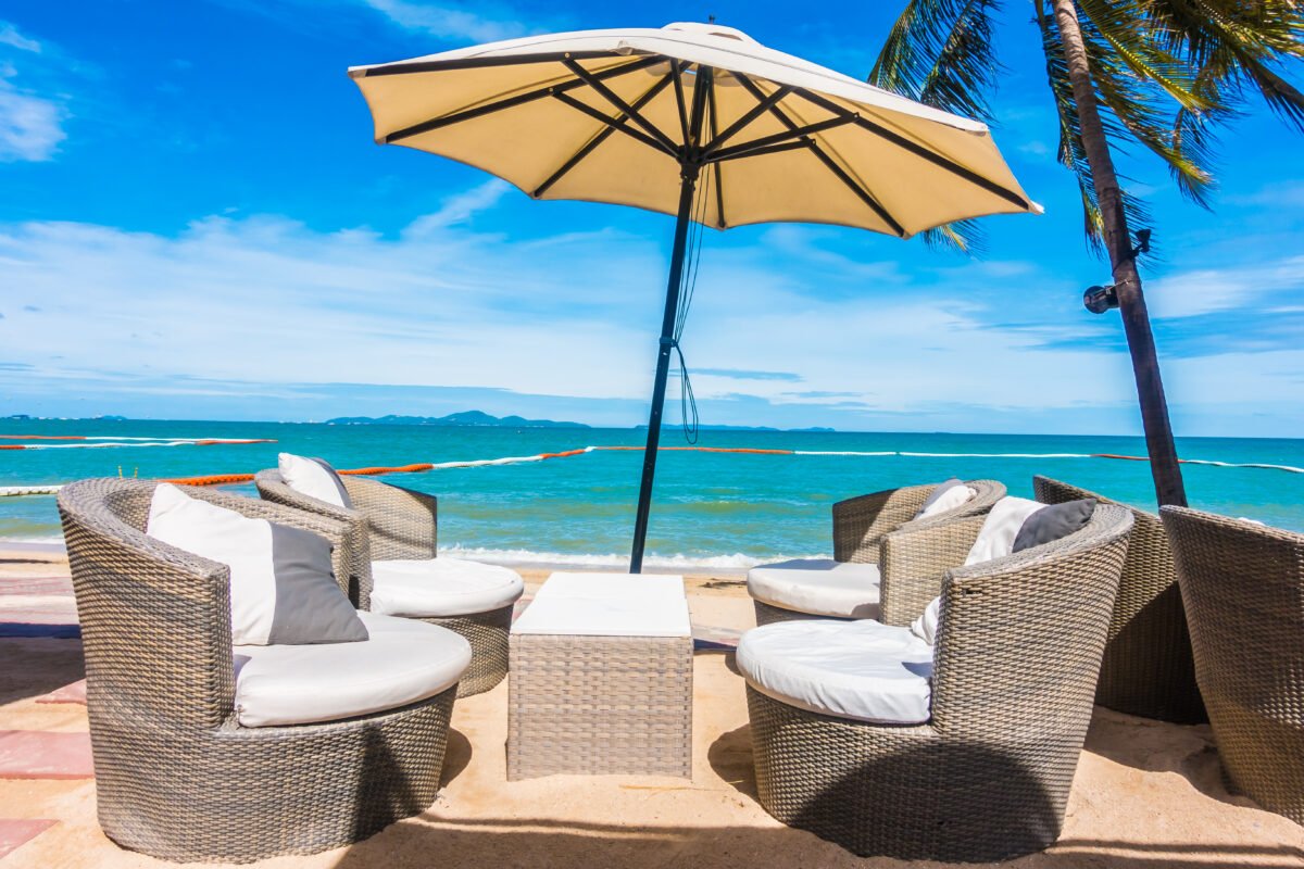 Umbrella and chair on the beautiful beach and sea with tropical palm tree on blue sky background